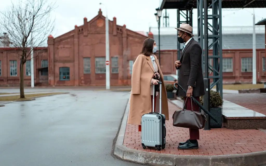 Two travellers with a suitcase waiting at the kerb