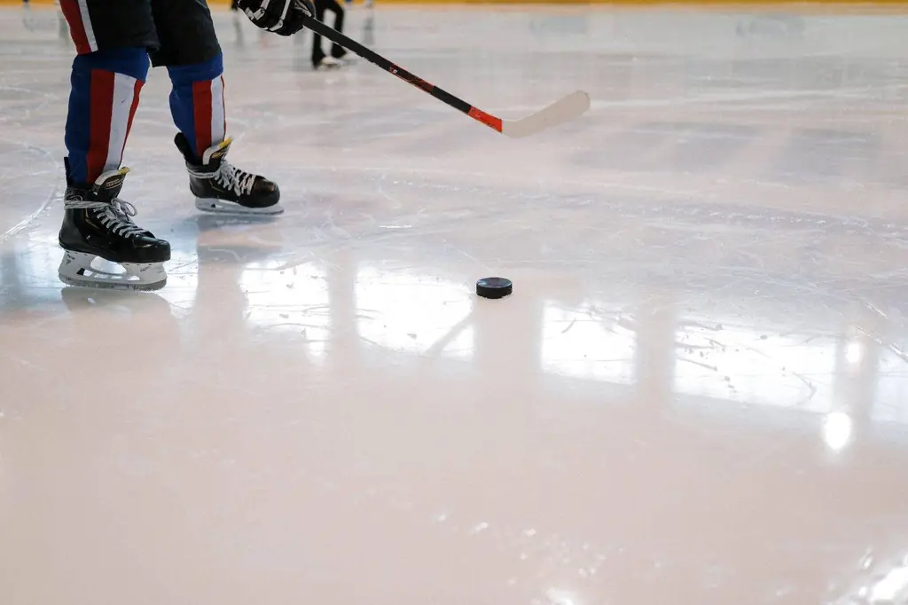 Shot of a hockey player maneuvering with stick and puck on ice rink