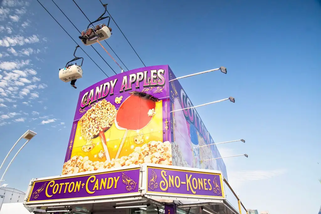 Colorful candy apples and sno-kones stand under blue sky at Toronto fair