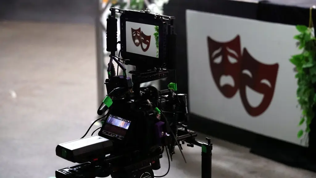Professional film camera capturing theater performance showing drama and comedy masks