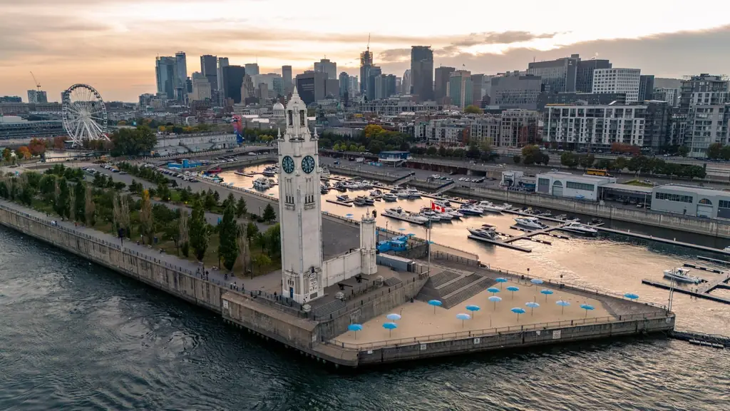 Aerial view of Montreal's Clock Tower beside the waterfront with a vibrant cityscape backdrop