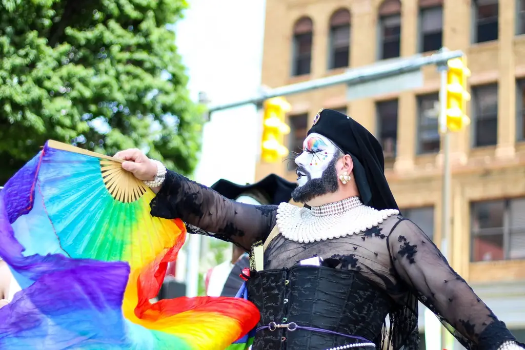 Colorful drag performer with rainbow flag celebrating at Pride Parade outdoors