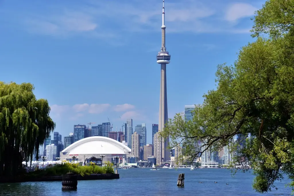 Toronto skyline with CN Tower and Rogers Centre, viewed from a waterfront park on a sunny day