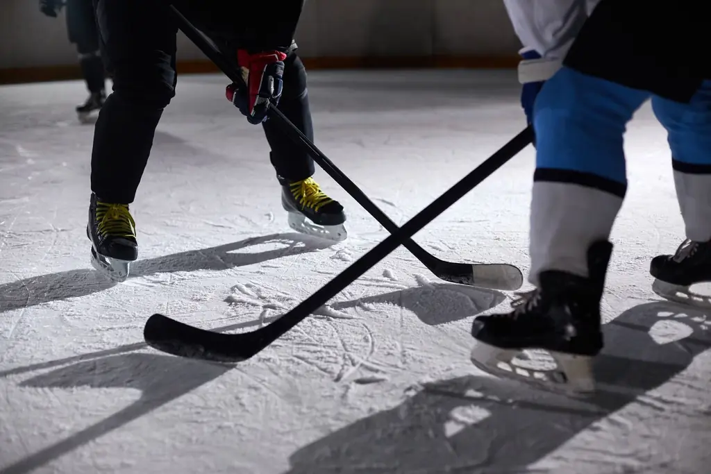 Close-up of hockey players battling for puck during an intense face-off on a lighted ice rink