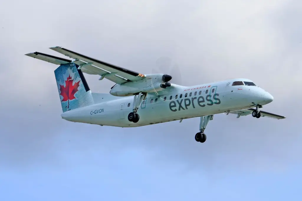 Air Canada Express plane soaring through the sky with a maple leaf design on a cloudy day