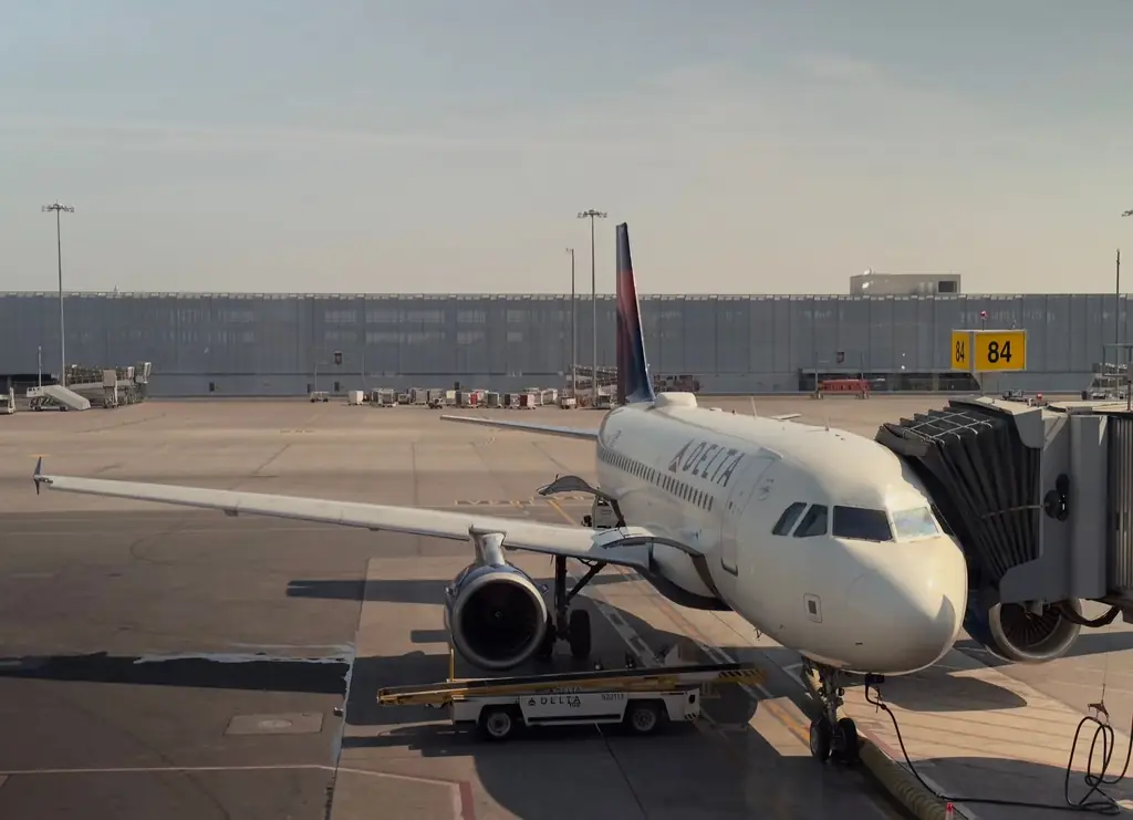 A Delta airplane docked at Montreal's airport gate 84 during daylight