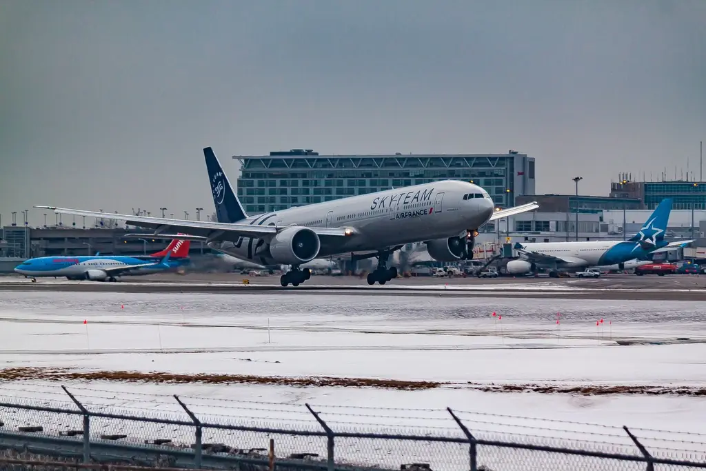 Jet taking off over snowy ground beside an airport terminal