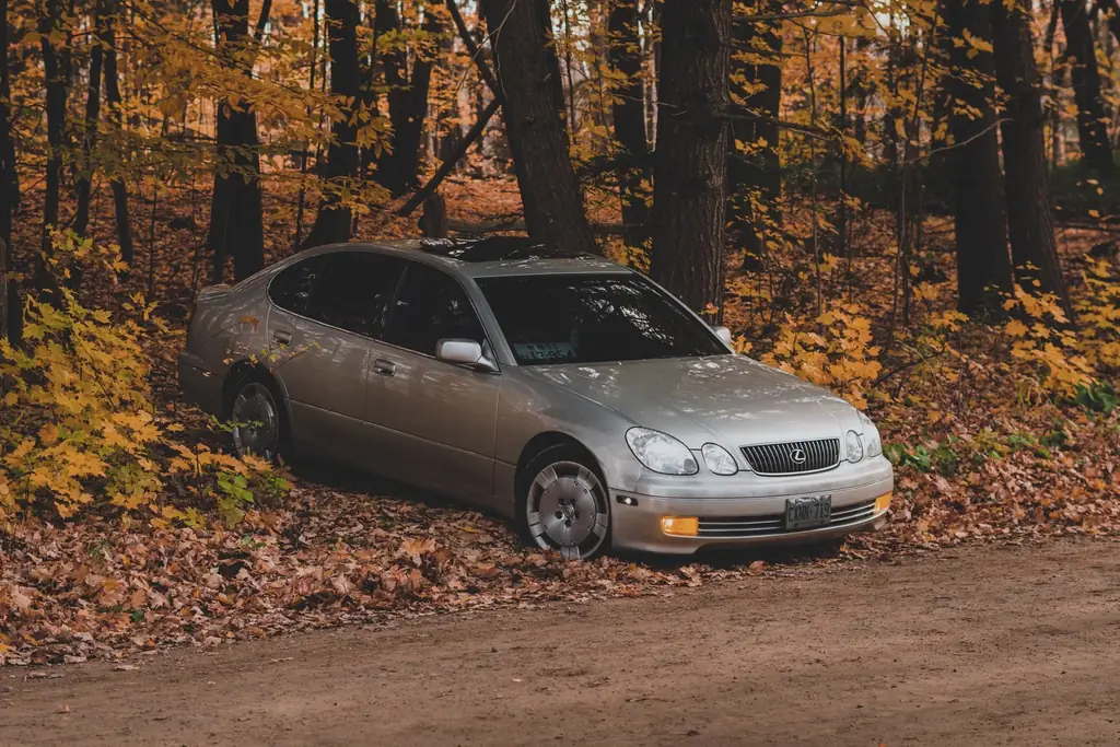 A luxury silver car parked on a dirt road surrounded by colorful autumn leaves in Brampton, Ontario