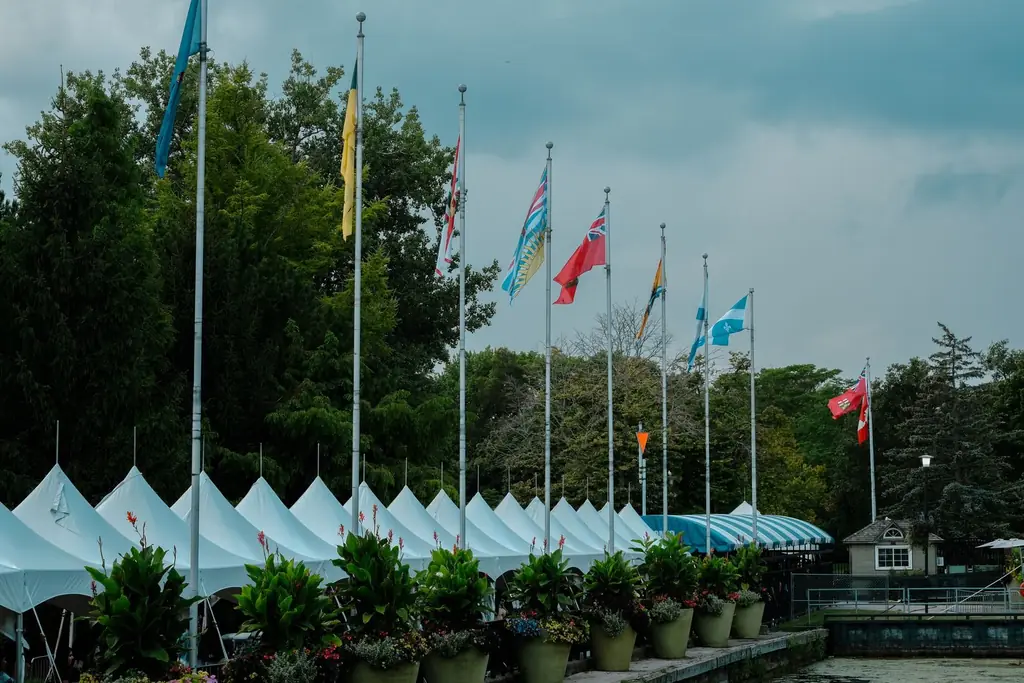 Multiple flags on poles against tents in a park, Toronto