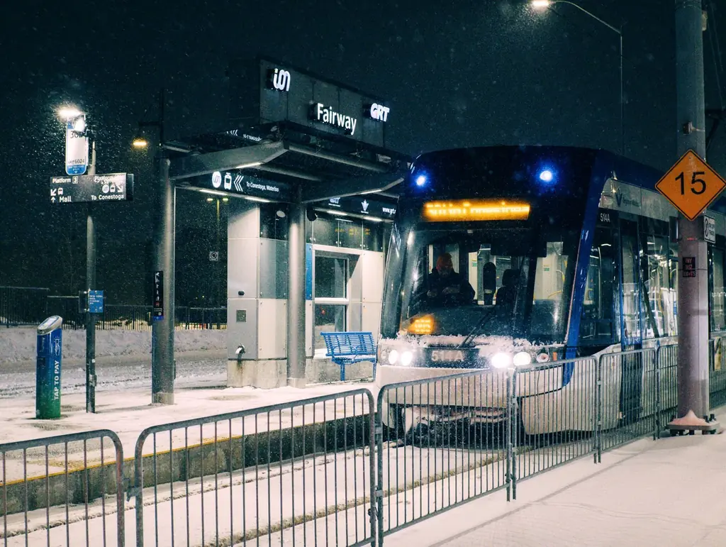 A snowy night at Fairway Station in Kitchener, Ontario with a light rail transit arriving