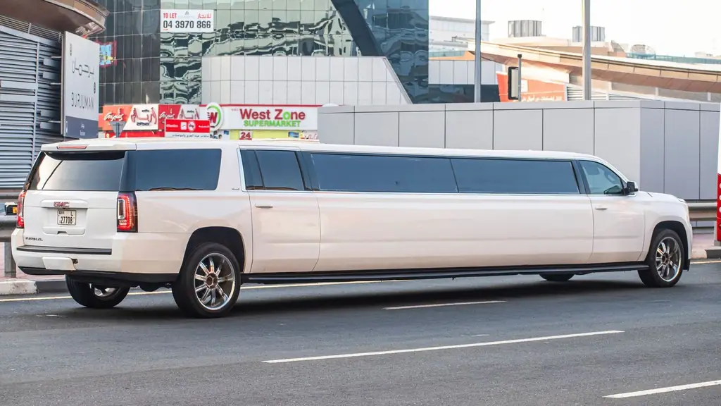 White GMC Yukon XL limousine parked on a bustling city street during the day