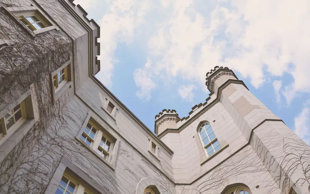 Upward view of a Gothic building with ivy-covered walls against a blue sky in London, Ontario