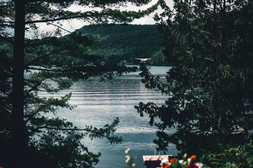 A seaplane flies over a tranquil lake in Mont-Tremblant