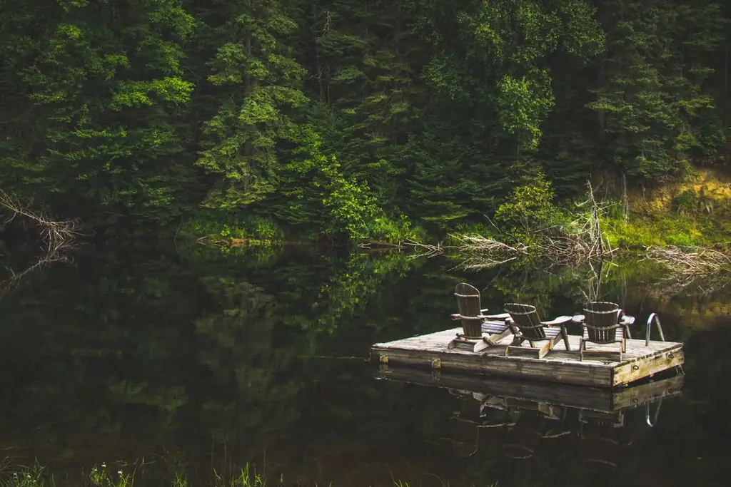 Summer scene of a wooden dock with chairs on a reflective lake in Bracebridge, Canada