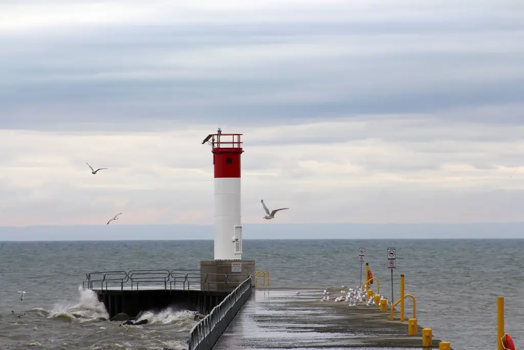 Red and white lighthouse at the end of a pier on Lake Ontario