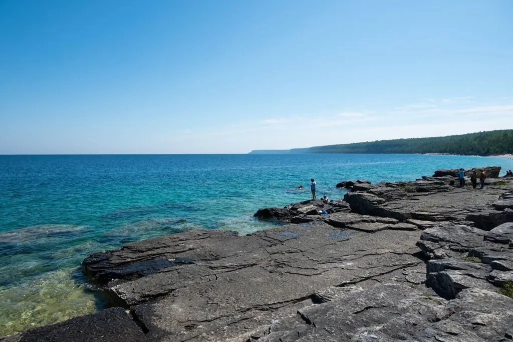 Rocky shoreline of Georgian Bay, Ontario, with clear turquoise waters and bright blue sky