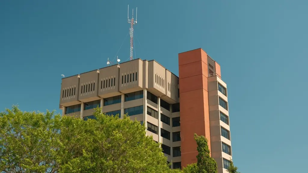 A tall modern office building with antennas in Oshawa, set against a clear blue sky