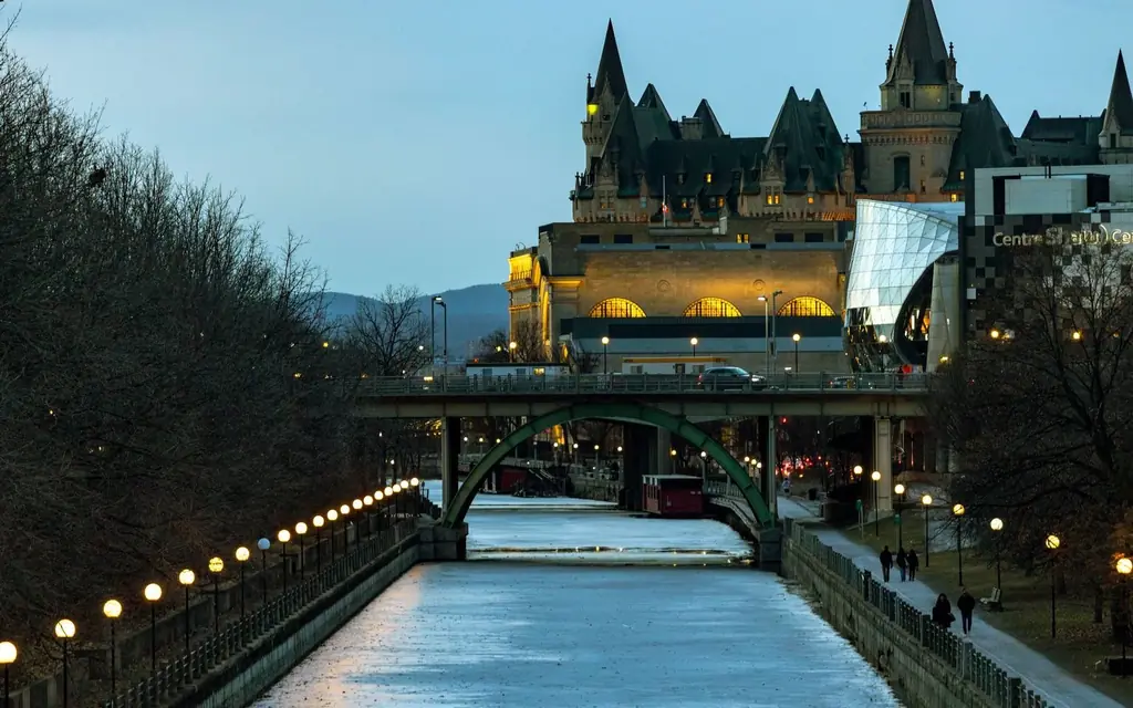 View of Ottawa's Rideau Canal at twilight in winter, showing architecture and city life