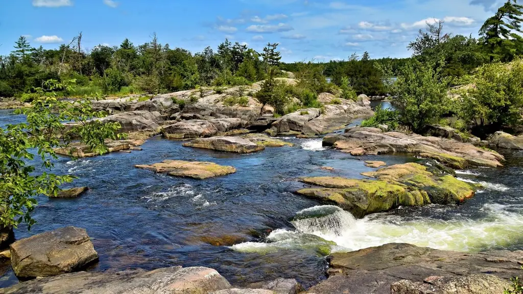 River flow over rocky terrain in Kawartha Lakes, Ontario under blue skies