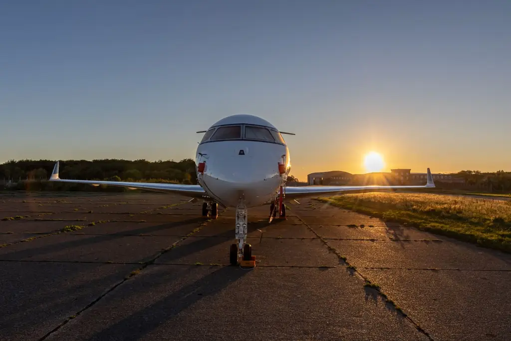 A private jet parked on the runway during a stunning sunset