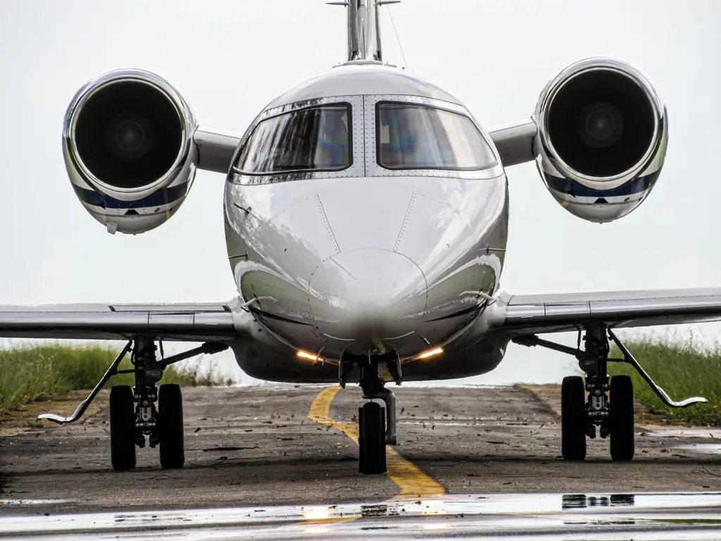 Front view of a sleek jet aircraft on a runway, ready for takeoff in daylight
