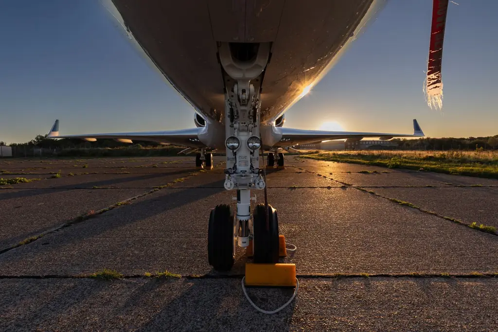Close-up of airplane landing gear during sunset on an empty runway