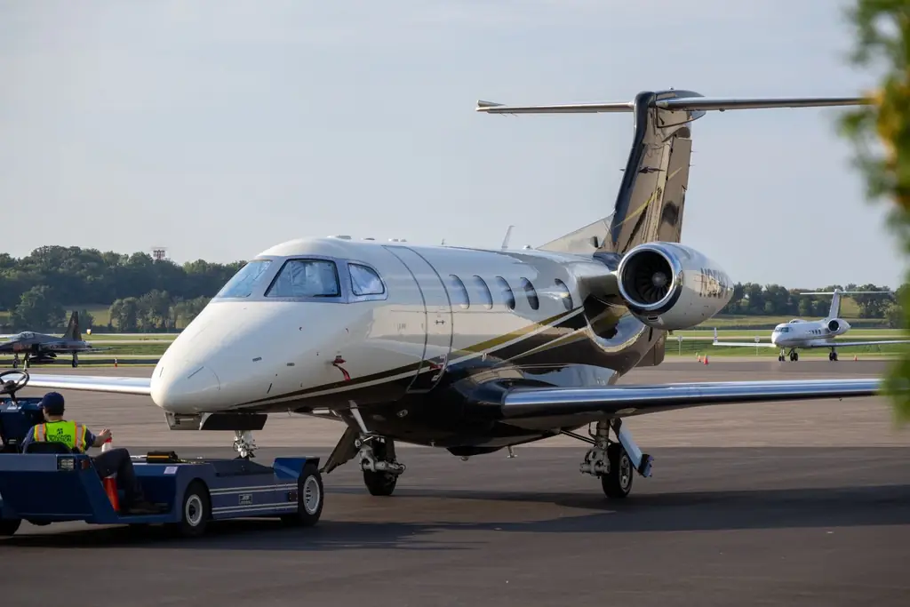 A private jet being serviced on an airport tarmac with clear skies
