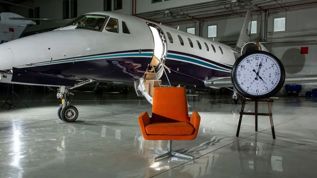 A private jet and modern furnishings inside an illuminated airport hangar
