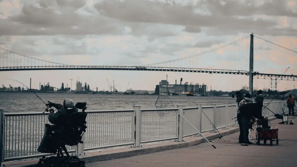 Fishermen enjoying a cloudy day by the river near the iconic Ambassador Bridge in Detroit