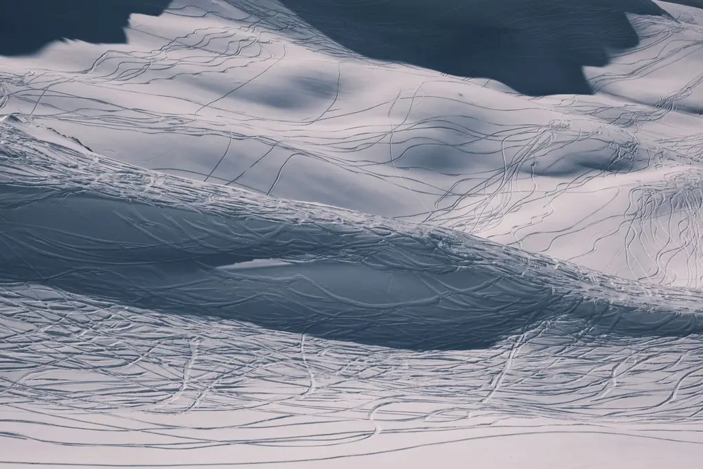 Aerial shot capturing ski tracks on a snowy winter mountainside