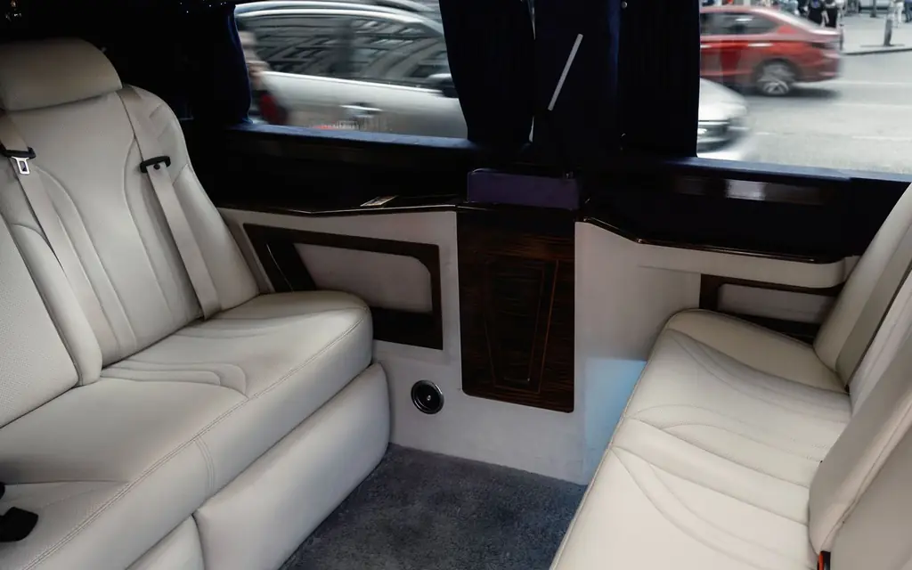 Interior view of a luxury limousine showcasing white leather seating with stylish design and amenities
