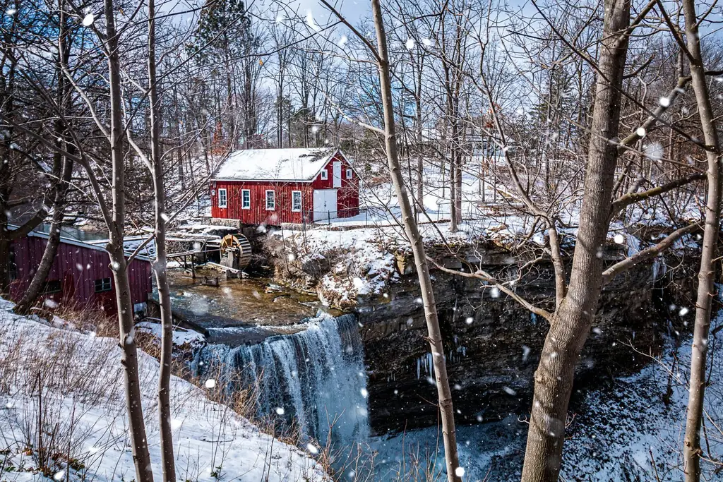 Red barn and watermill above a waterfall in snowy Niagara countryside near St. Catharines