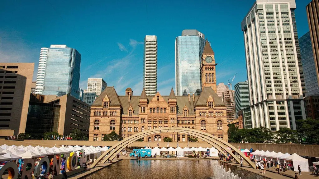 Toronto's historic Old City Hall and Nathan Phillips Square with reflecting pool under blue sky
