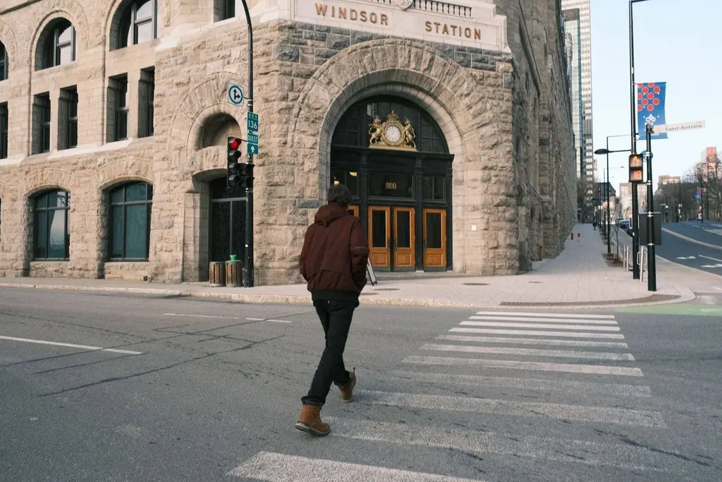 Man walking across a crosswalk in front of iconic Windsor Station in Montreal