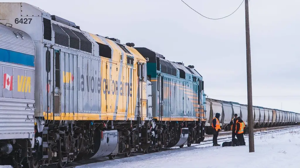 VIA Rail train crossing a snowy field in Canada during winter with railway workers