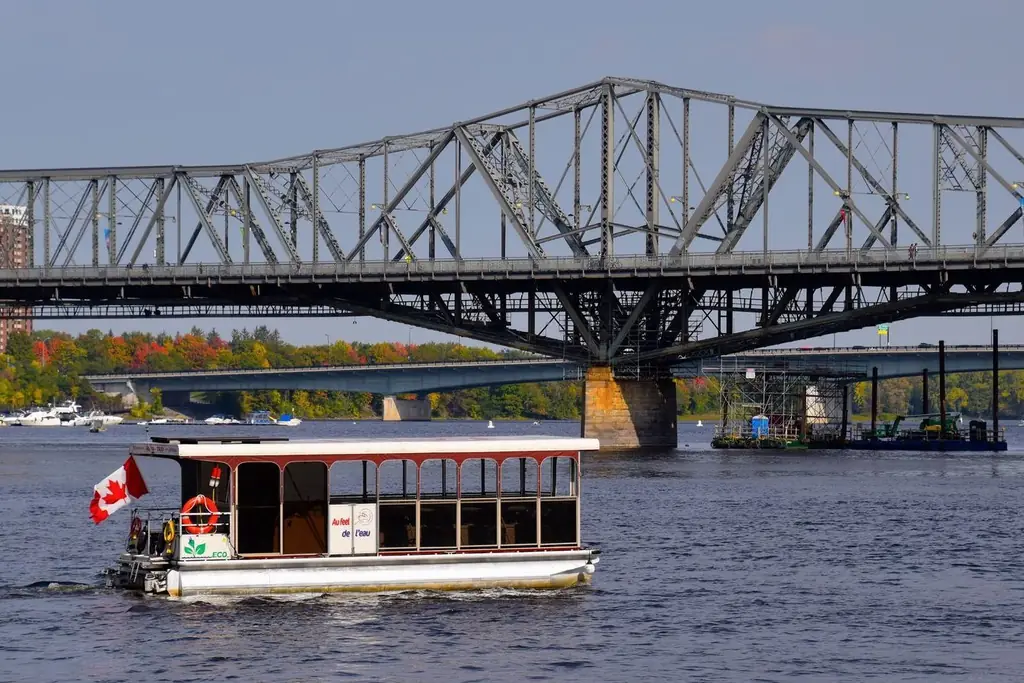 Ferry crossing Ottawa River by Alexandra Bridge with Canadian flag